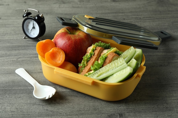 Lunch box and tasty food on gray textured background