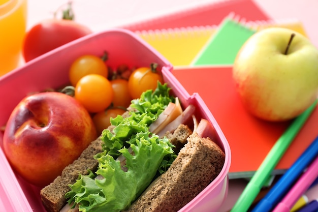 Lunch box con cibo appetitoso e cancelleria sul tavolo, primo piano