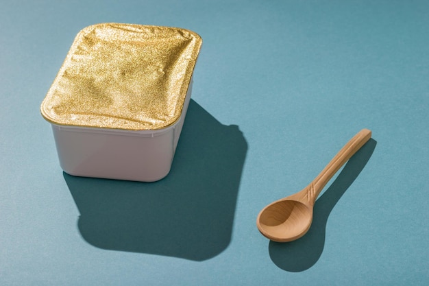 Lunch box with peanut paste and a wooden spoon on a blue background