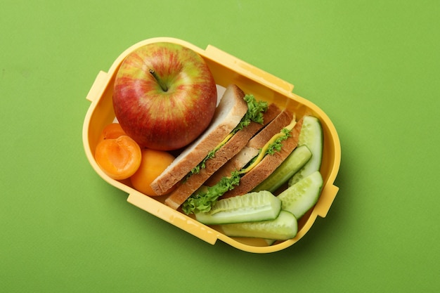 Lunch box with tasty food on green background