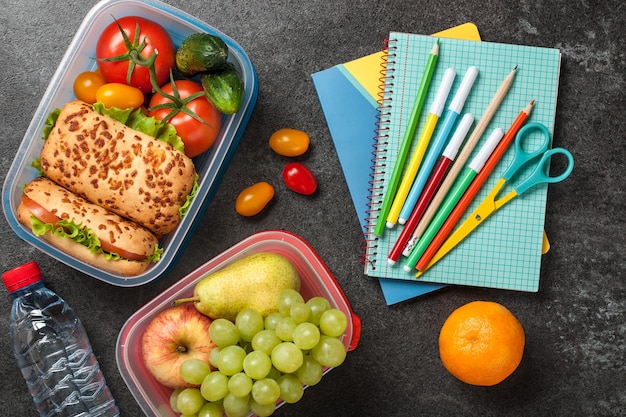 Lunch boxes and school supplies on black