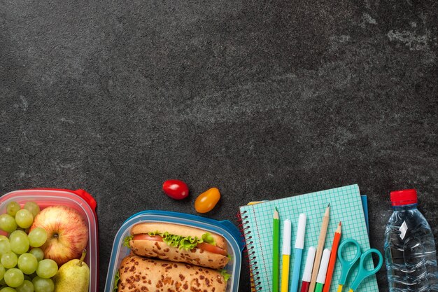 Foto scatole per il pranzo e materiale scolastico su nero