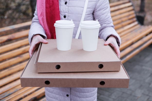 写真 昼休みの女の子が公園でパイを食べてコーヒーを飲みながら、ベンチフードデリバリーをしたい...