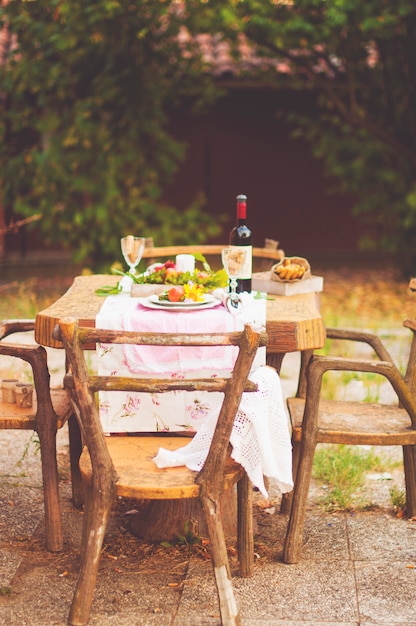 Foto pranzo in giardino con vino e frutta. cena romantica all'aria aperta. foglie autunnali di fiori. scrapbooking bellissimo tavolo. foto d'epoca.