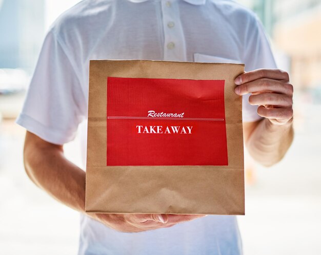 Photo lunch is ready cropped shot of a delivery man holding a restaurant takeaway