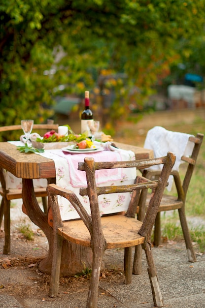 Lunch is romantisch in de herfsttuin, sfeer van vakantie en gezelligheid. Herfst diner in de open lucht met wijn en fruit. Decortafel met bloemen en granaatappel.