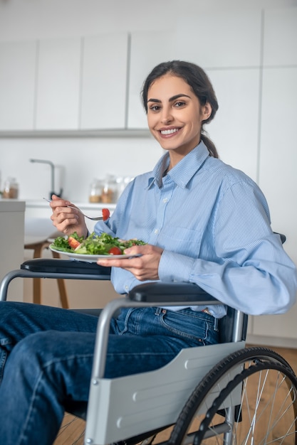 ランチタイム。昼食をとっている自宅でポジティブな障害のある若い女性