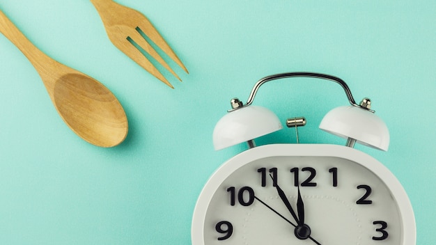 Photo lunch time with alarm clock on blue background.