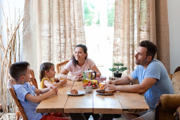 Lunch twee ouders en twee kinderen zitten aan een tafel in de eetkamer en communiceren