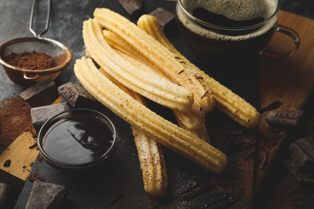 暗いテーブルでチュロスとチョコレートと一緒にランチ