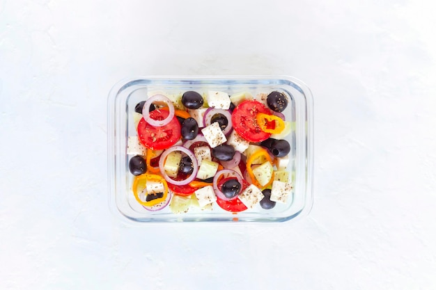 Lunchbox met Griekse salade op witte achtergrond