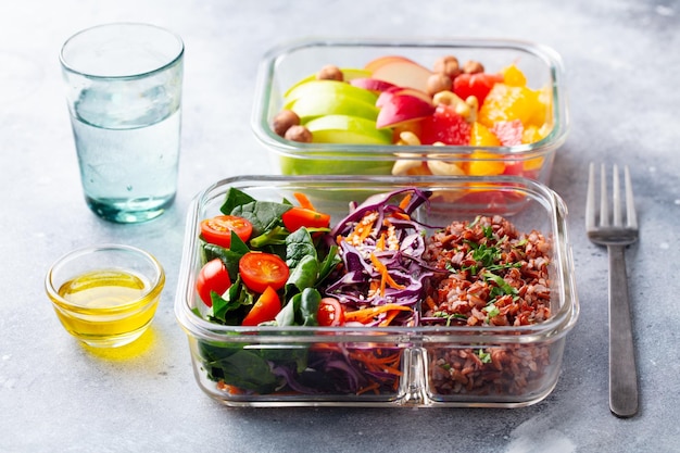 Foto lunchbox met groenten, bruine rijst en fruitsalade gezond eten grijze achtergrond