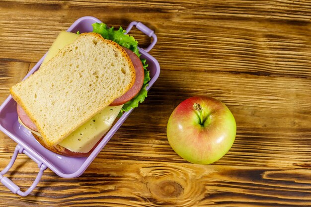 Lunchbox met sandwiches en appel op een houten tafel Bovenaanzicht