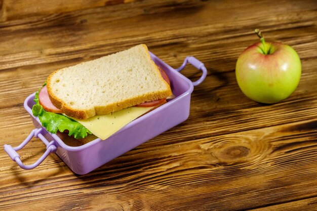 Lunchbox met sandwiches en appel op een houten tafel