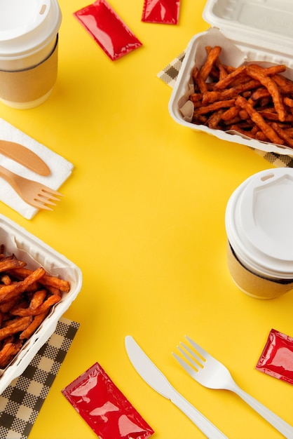 Lunchboxes with fries sweet potato drink and sauce on yellow table flat lay top view food delivery c