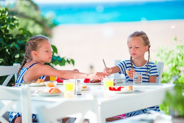 Lunchtijd. Meisjes ontbijten op terras met uitzicht op zee