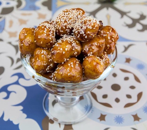 Luqaimat or Gemat sweet balls with sesame seeds served in dish isolated on table top view of arabic dessert food