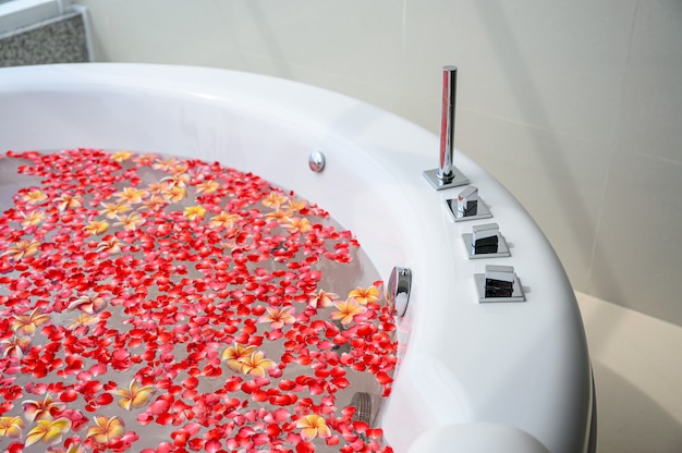 Luxe badkuip met kleurrijke bloem in water met uitzicht op zee