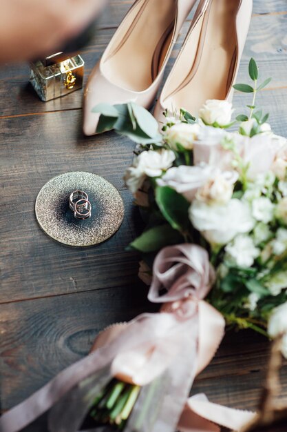 Foto luxe bruidsboeket naast de ringen van de bruid en bruidegom. de schoenen van de bruid met hakken