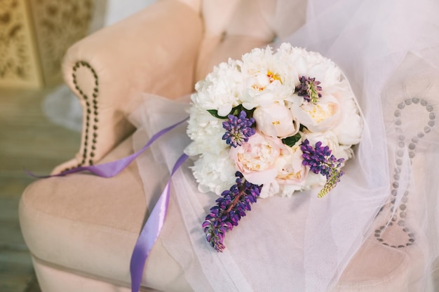 Luxe bruidsboeket samenstelling van paars roze en witte bloemen pioenen in een zachte stoel