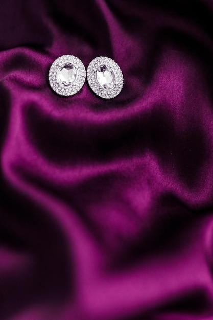 Luxe diamanten oorbellen op donkerroze zijde stof vakantie glamour sieraden aanwezig