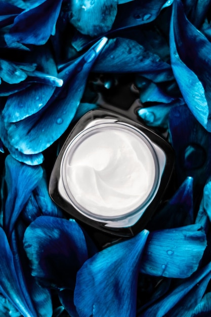 Luxe gezichtscrème vochtinbrengende crème voor gezichtshuid op blauwe bloem achtergrond bloemen essense spa cosmetica en schoonheidsemulsie voor huidverzorging merkproduct