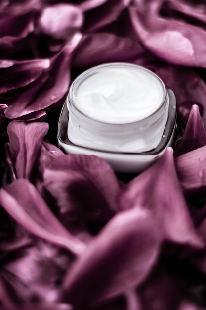 Luxe gezichtscrème vochtinbrengende crème voor gezichtshuid op roze bloem achtergrond bloemen essense spa cosmetica en schoonheidsemulsie voor huidverzorging merkproduct