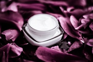 Luxe gezichtscrème vochtinbrengende crème voor gezichtshuid op roze bloem achtergrond bloemen essense spa cosmetica en schoonheidsemulsie voor huidverzorging merkproduct