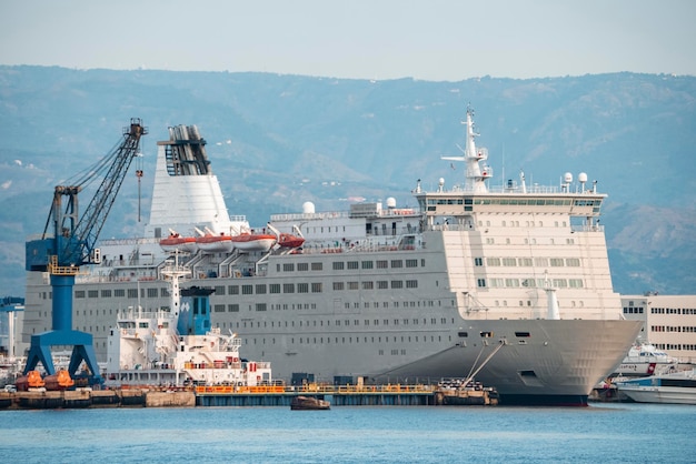 Luxe groot cruiseschip afgemeerd aan de haven van Messina met bergen op de achtergrond