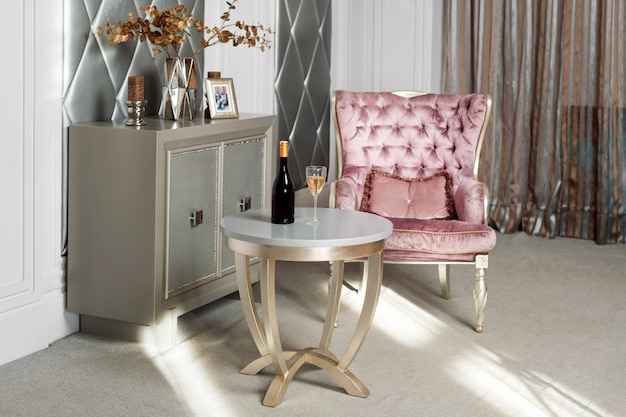 Luxe interieur. Luxe roze fluwelen fauteuil, antiek bewerkte meubels, klassiek interieur. Wijn geserveerd in een stijlvol restaurant dat wacht op een gast.