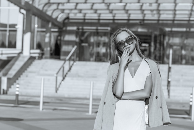 Luxe jong model met lang haar draagt een zonnebril en jas. Monochrome kleur. Ruimte voor tekst