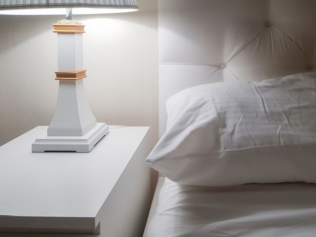 Foto luxe modern ontwerp van een lichte slaapkamer met een nachtkastje en een nachtlampje en een kussen op het bed, klaar om naar bed te gaan