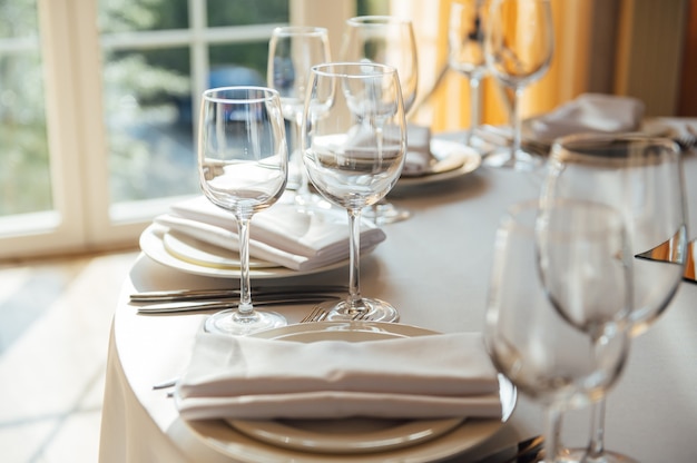 Luxe restaurant. Luxe interieur, witte tafels, serveerschalen en glazen voor gasten.
