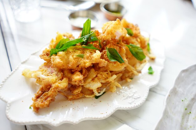 Luxe snack en voorgerecht gebakken knapperige inktvis op witte schijf, klaar om te eten.