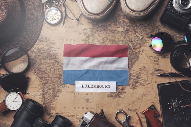 Photo luxembourg flag between traveler's accessories on old vintage map. overhead shot