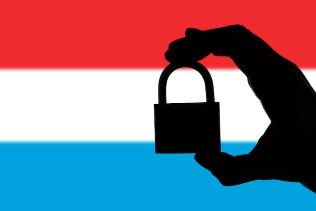 Luxemburgse veiligheid Silhouet van de hand met een hangslot boven de nationale vlag