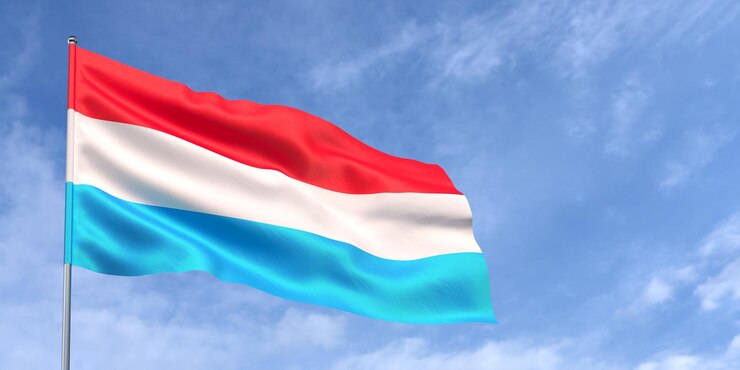 Luxemburgse vlag op vlaggenmast op blauwe hemelachtergrond De Luxemburgse vlag wappert in de wind tegen een hemel met witte wolken Plaats voor tekst 3d illustratie