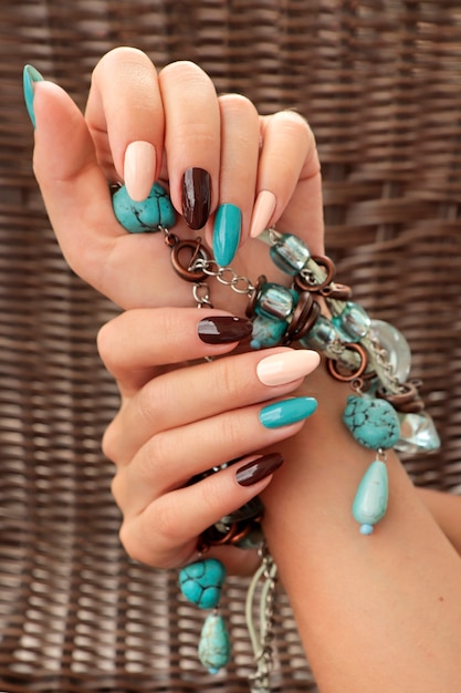 Luxurious beige brown manicure with turquoise designs on long nails with accessory.