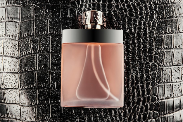 Luxurious bottle of perfume on black crocodile skin texture