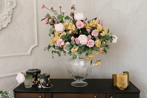 A luxurious bouquet of flowers in a glass vase stands on the dresser. home interior decor