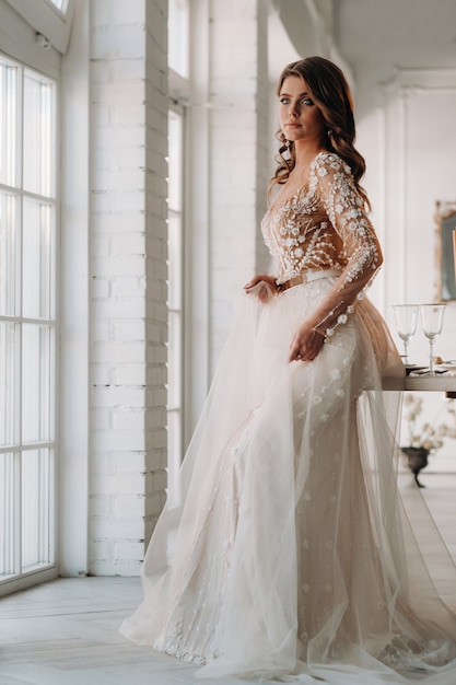 A luxurious bride in a wedding dress in the morning in her interior