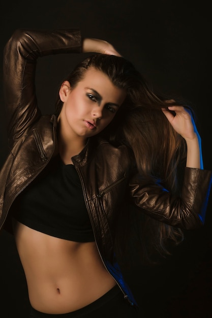 Luxurious brunette model with art makeup in leather jacket at studio