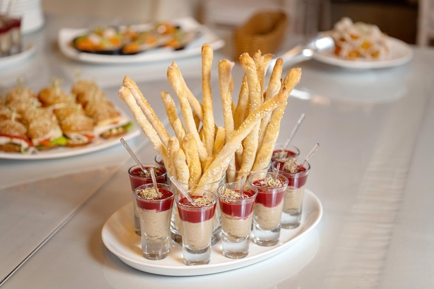 Luxurious catering table Breadsticks sprinkled with white sesame seeds Snacks in glasses Clouseup