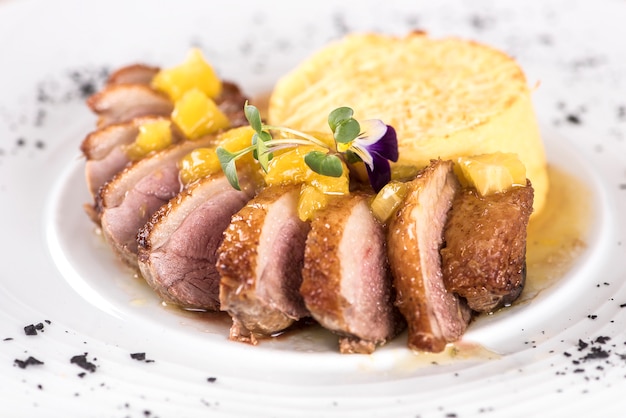 Luxurious dish with slices of duck breast, pineapple pieces, sweet sauce, potato puree