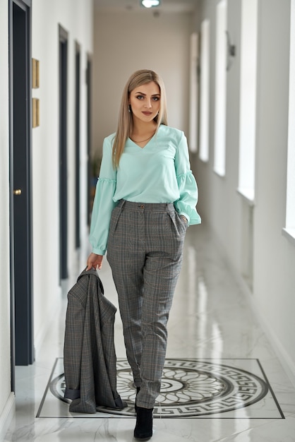 Luxurious girl posing in a business style in the hotel corridor.