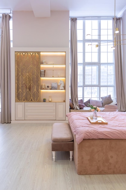 高価で広々とした明るくスタイリッシュなアパートの豪華でモダンなベッドルームのインテリア。布張りの家具と装飾照明、柔らかなパステルカラーと居心地の良い雰囲気