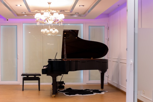 Luxurious music room with grand piano and chandelier with colorful lighting.