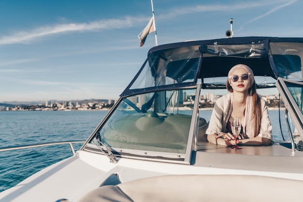 A luxurious rich woman in sunglasses enjoys relaxation on her yacht sails on the Caribbean sea