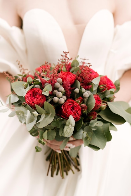 Роскошный свадебный букет с красными розами в руках невесты