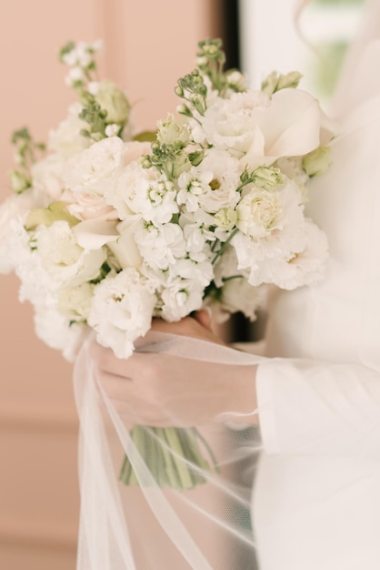 A luxurious wedding bouquet with white roses in the hands of the bride